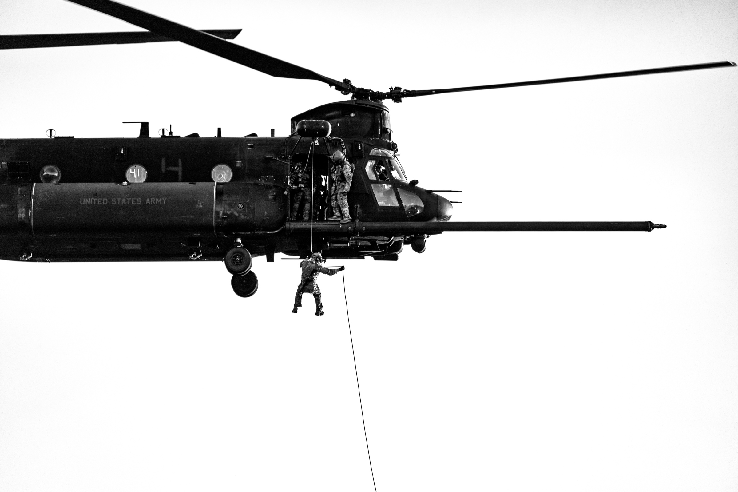 Soldiers rappelling from a hovering Chinook helicopter